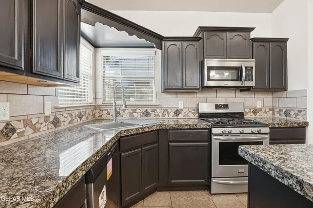 a kitchen with stainless steel appliances granite countertop a sink stove microwave and cabinets
