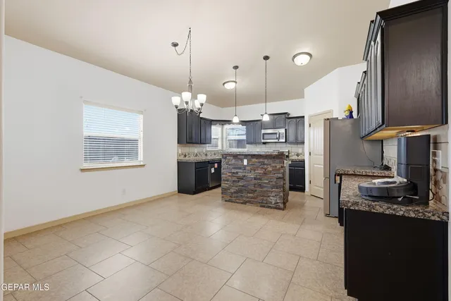 a large kitchen with kitchen island granite countertop a stove a sink a counter space and cabinets