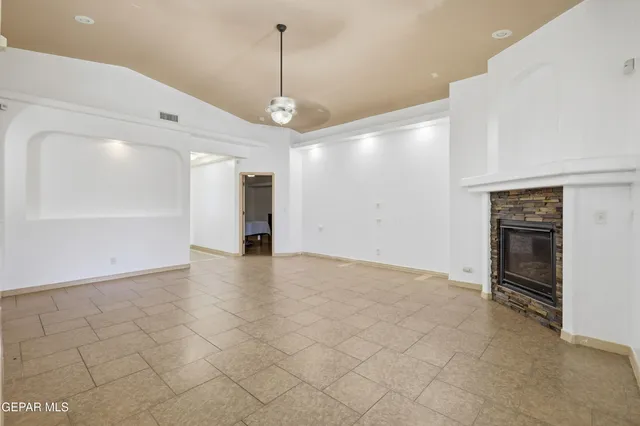 a view of an empty room and a kitchen