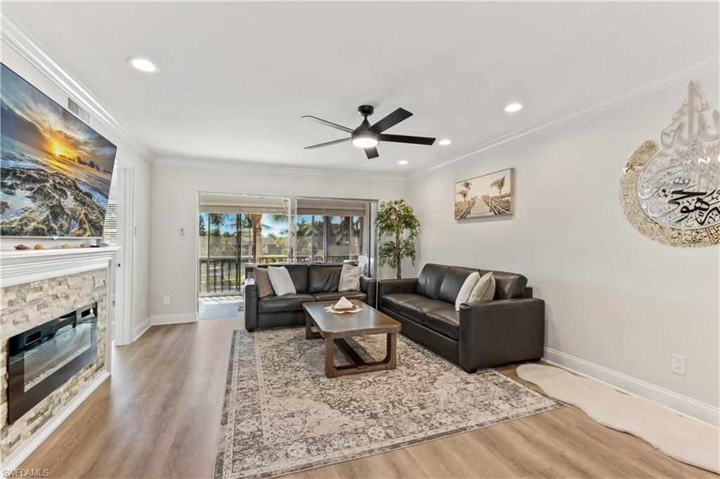 1020 Palm View Drive, Unit C302 Naples, FL 34110 - Photo 4 of 19 Living area with light wood-style floors, ceiling fan, crown molding, a stone fireplace, and recessed lighting