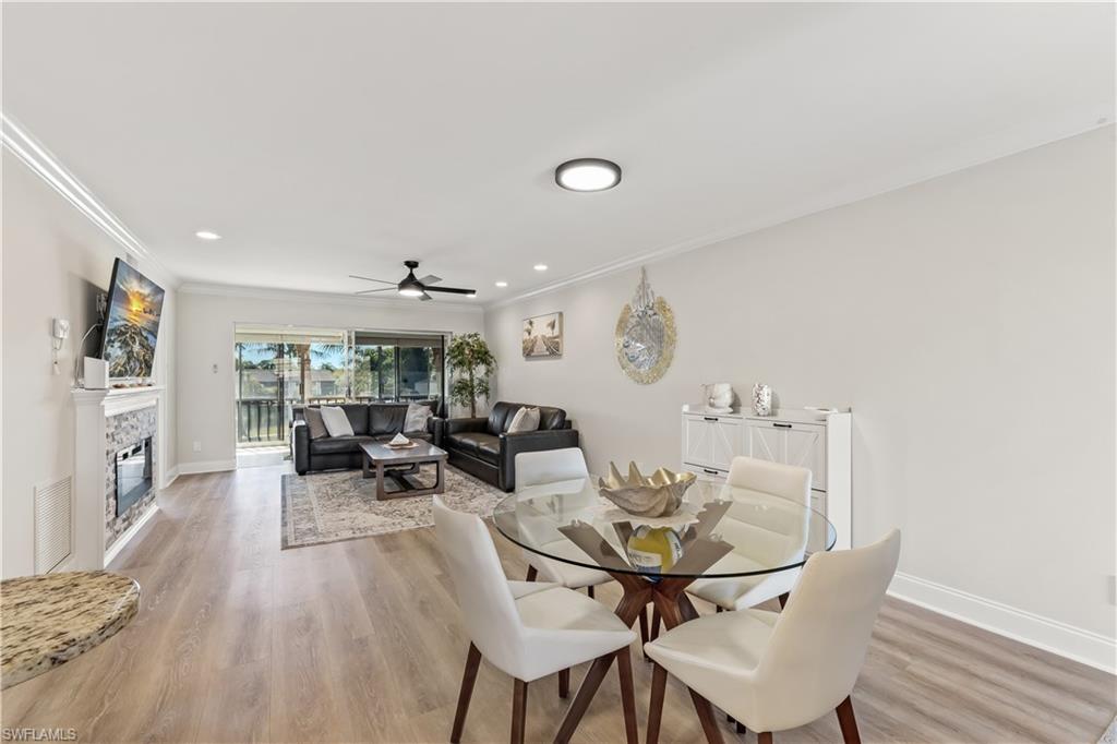 1020 Palm View Drive, Unit C302 Naples, FL 34110 - Photo 7 of 19 Dining area featuring light wood-type flooring, crown molding, a glass covered fireplace, recessed lighting, and ceiling fan