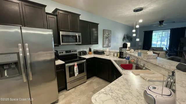 a kitchen with stainless steel appliances kitchen island granite countertop a refrigerator a stove a sink and a dining table with wooden floor