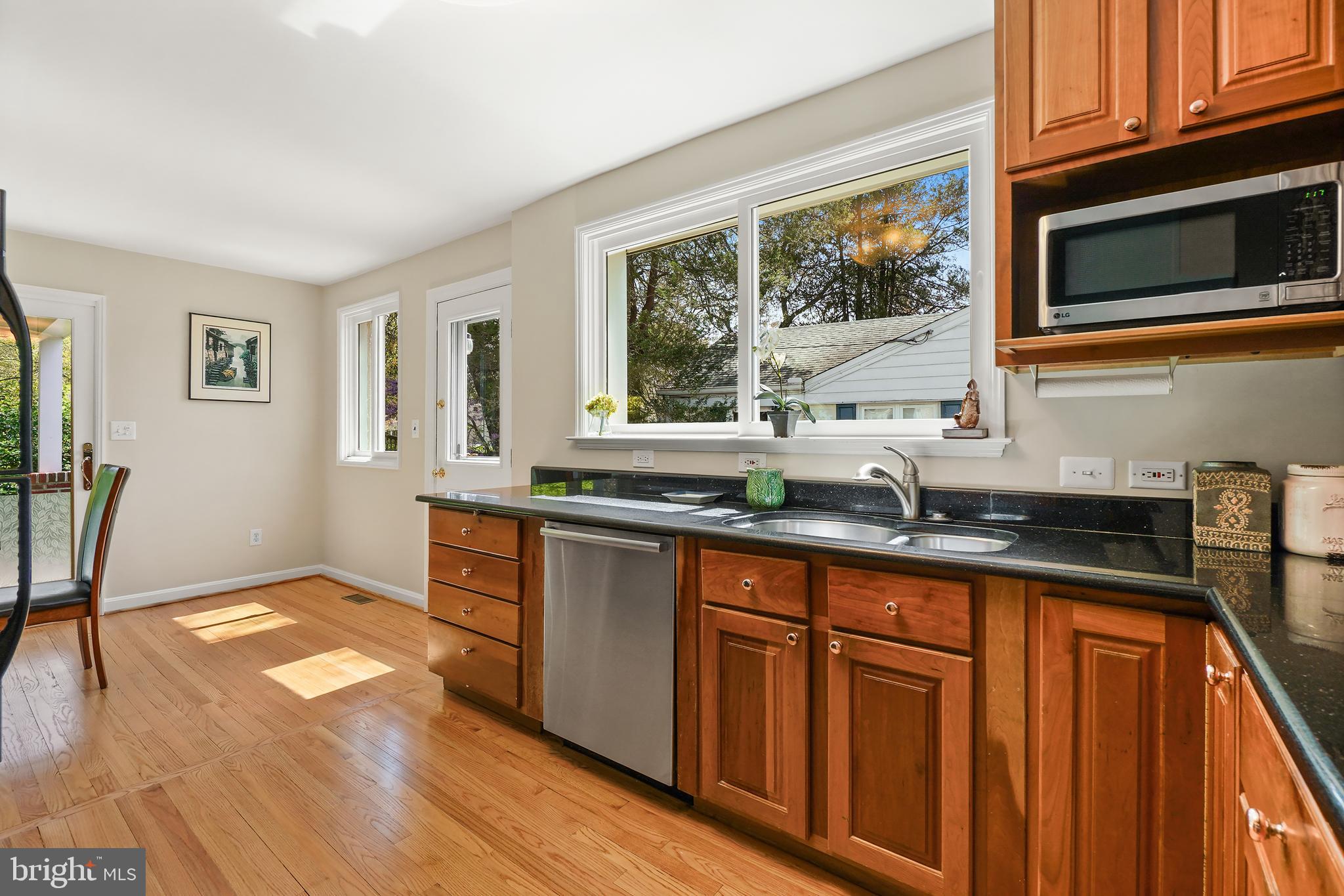 8600 Grubb Road Chevy Chase, MD 20815 - Photo 14 of 36 a kitchen with granite countertop wooden cabinets a sink a window and stainless steel appliances