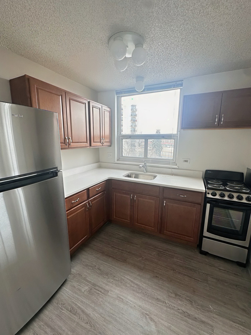 8975 West Golf Road, Unit 321 Niles, IL 60714 - Photo 3 of 10 a kitchen with stainless steel appliances granite countertop a refrigerator a sink dishwasher a stove with wooden floors
