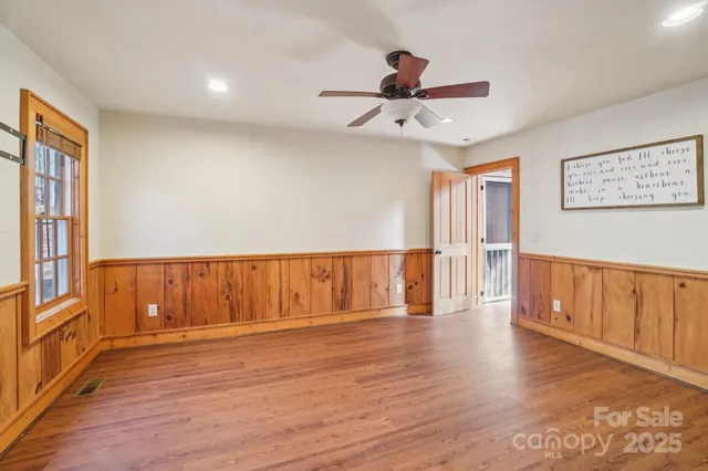 a view of an empty room with a window and wooden floor
