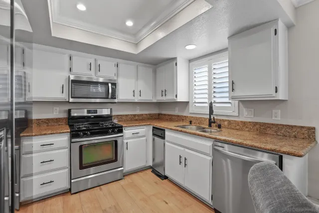 a kitchen with stainless steel appliances granite countertop a sink dishwasher a stove and a microwave oven with cabinets