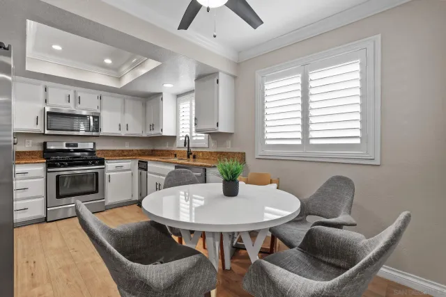 a kitchen with stainless steel appliances kitchen island granite countertop a sink a stove a dining table and chairs