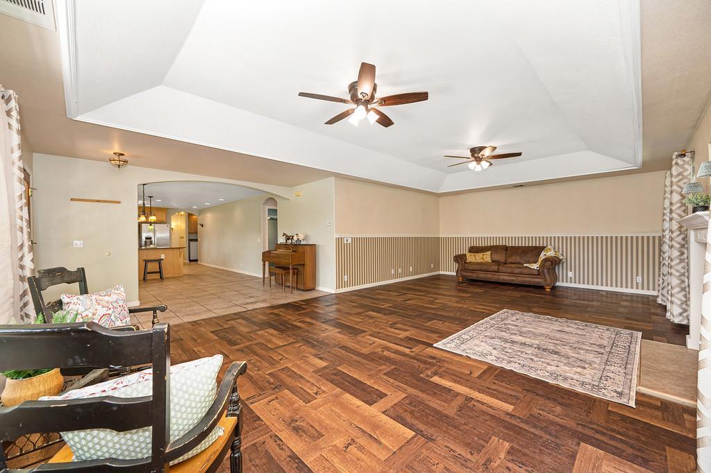 6181 Lambert Lane El Dorado, CA 95623 - Photo 21 of 80 living area featuring a tray ceiling, a ceiling fan, arched walkways, and dark wood finished floors