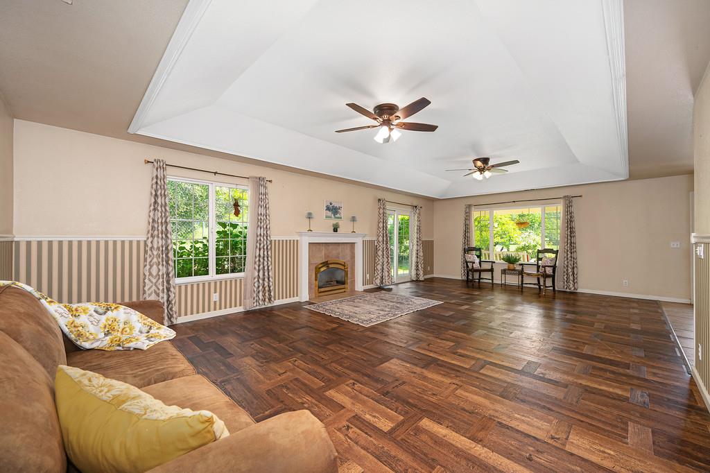 6181 Lambert Lane El Dorado, CA 95623 - Photo 22 of 80 living room with a tray ceiling, parquet flooring, ceiling fan, healthy amount of natural light, and a tile fireplace