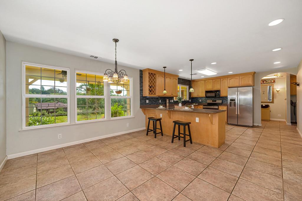 6181 Lambert Lane El Dorado, CA 95623 - Photo 24 of 80 a kitchen with stainless steel appliances kitchen island granite countertop a refrigerator a stove a sink and a dining table with wooden floor