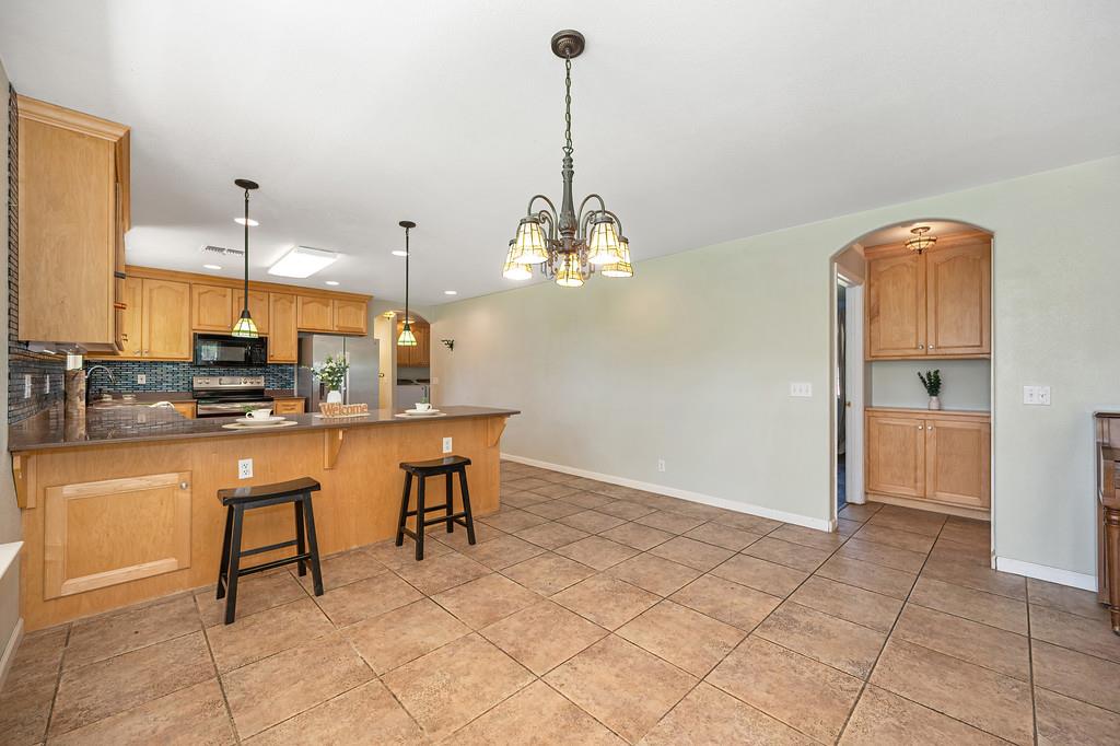 6181 Lambert Lane El Dorado, CA 95623 - Photo 25 of 80 kitchen with a peninsula, arched walkways, stainless steel appliances, a chandelier, and light tile patterned floors