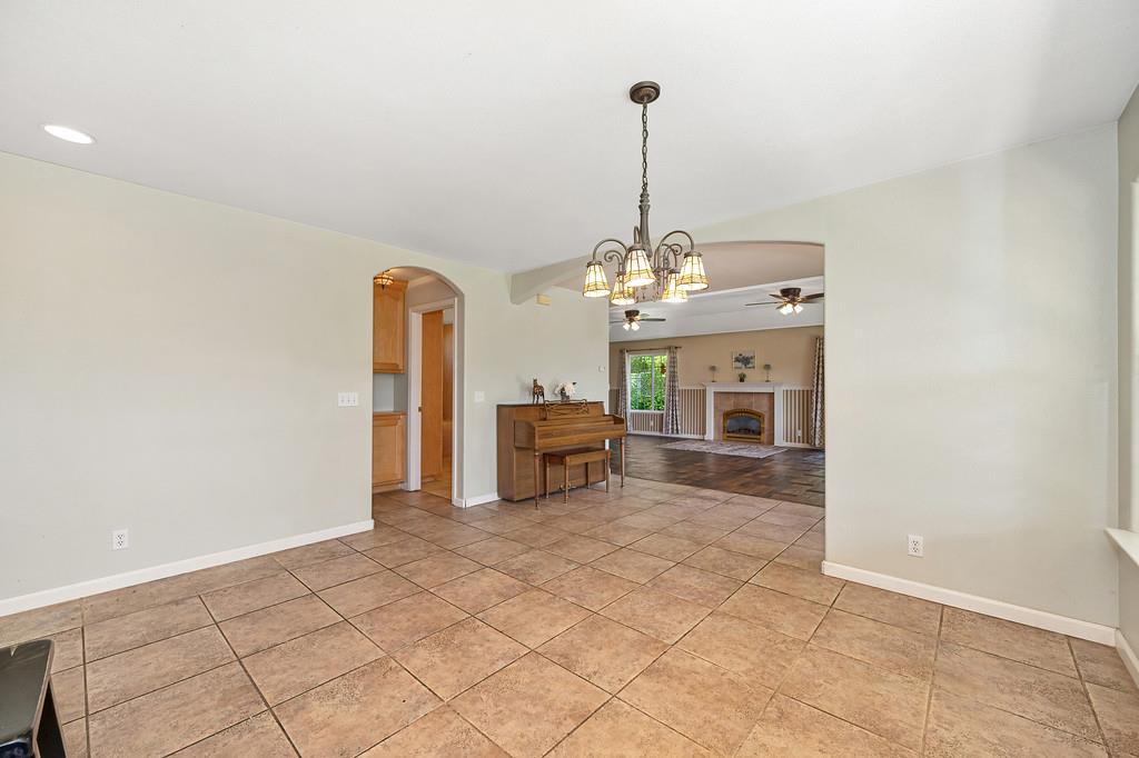 6181 Lambert Lane El Dorado, CA 95623 - Photo 29 of 80 dining area featuring suspended lighting, a ceiling fan, arched walkways, a fireplace, and light tile patterned floors