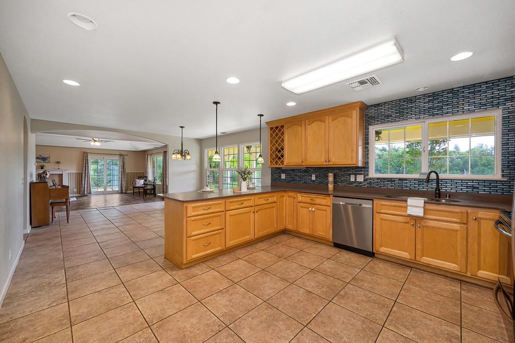 6181 Lambert Lane El Dorado, CA 95623 - Photo 79 of 80 kitchen with open floor plan, light tile patterned floors, pendant lighting, a peninsula, and backsplash