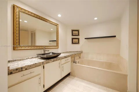 a bathroom with a granite countertop sink mirror and a bathtub