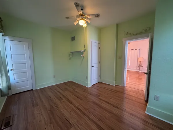 an empty room with wooden floor and windows