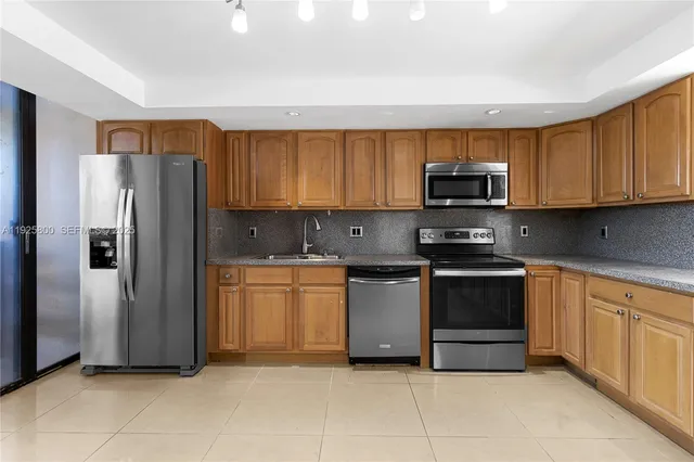 a kitchen with stainless steel appliances granite countertop a refrigerator and a stove top oven
