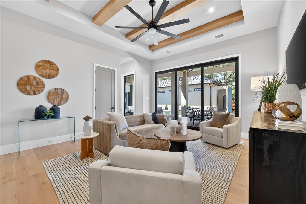11028 Edgemere Road Dallas, TX 75230 - Photo 21 of 40 Game/ living down area featuring wood-finish flooring, a tray ceiling with exposed wood beams, and a modern ceiling fan