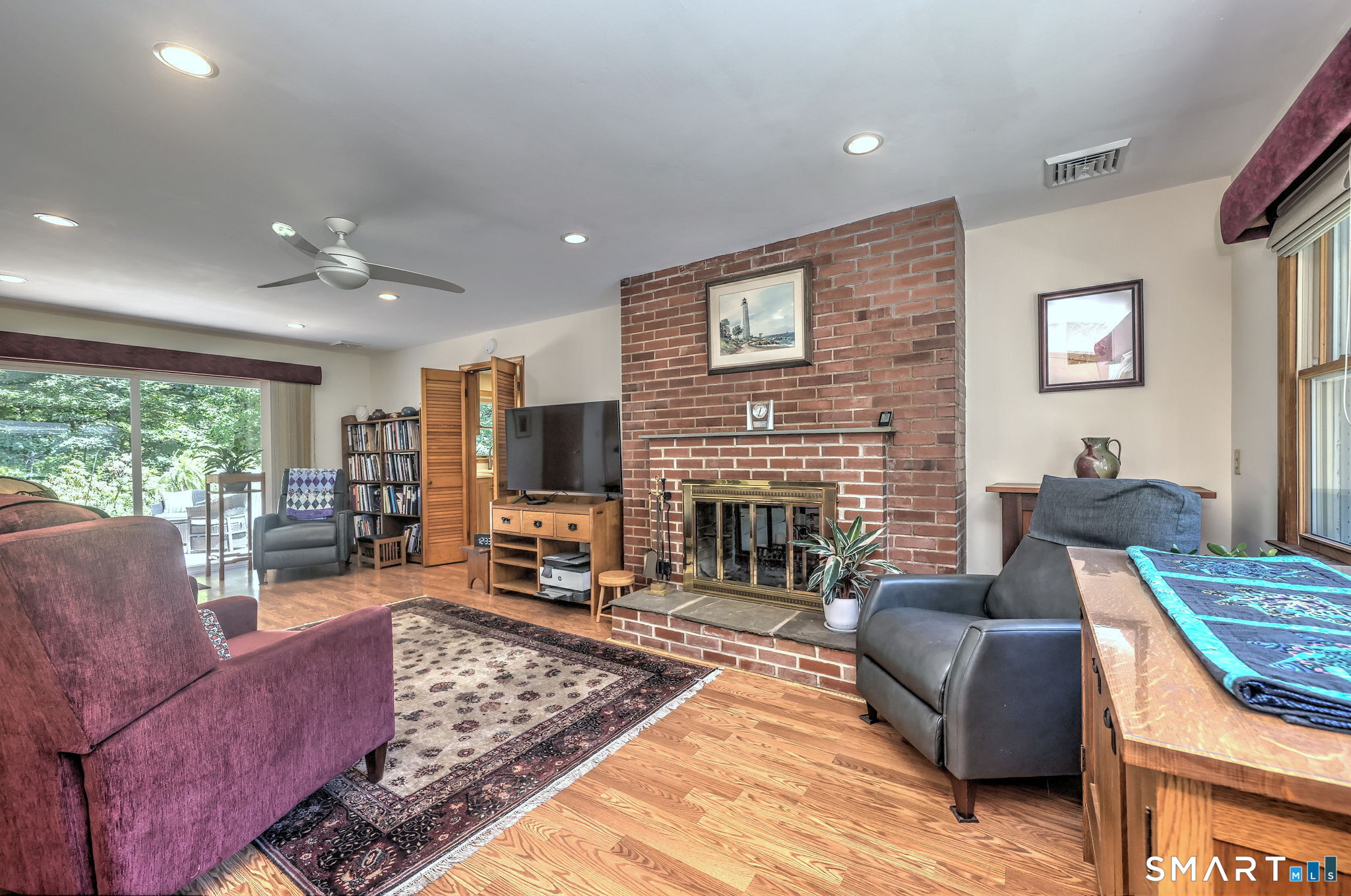 25 Mountain View Road Bethany, CT 06524 - Photo 13 of 27 This space has beautiful hardwood floors, a brick floor to ceiling pass-through fireplace and ceiling fan.