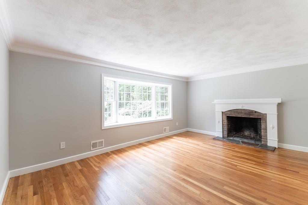 175 Powers Road Sudbury, MA 01776 - Photo 6 of 32 an empty room with wooden floor fireplace and windows
