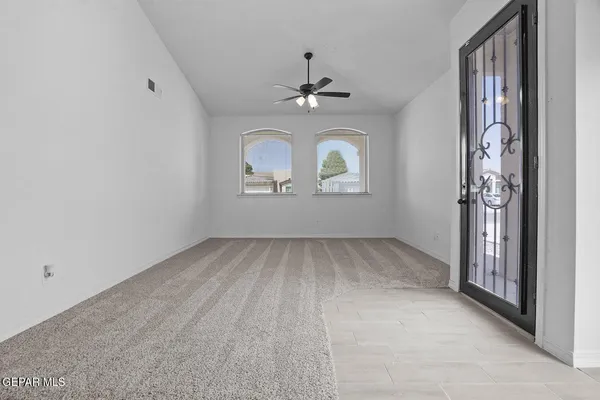 an empty room with windows and ceiling fan