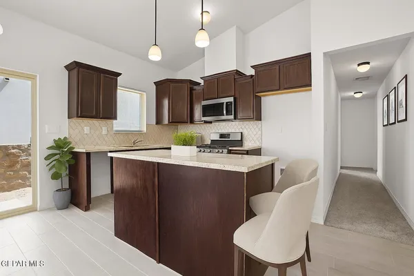 a kitchen with a refrigerator a microwave a sink and chairs
