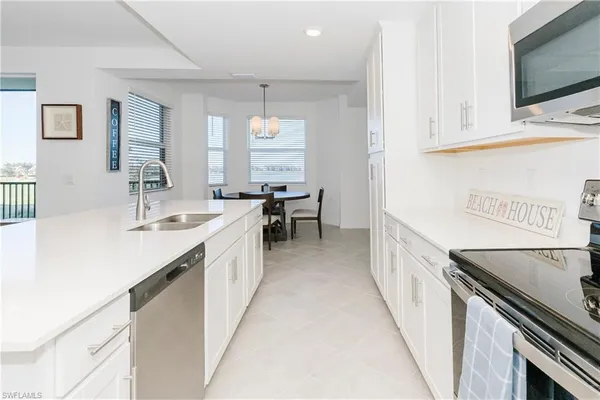 a large white kitchen with a sink and dishwasher a stove with wooden floor