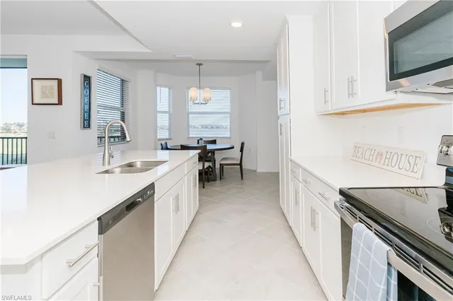 a large white kitchen with a sink and dishwasher a stove with wooden floor