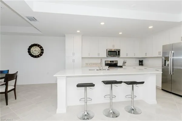 a kitchen with stainless steel appliances granite countertop a sink a stove a refrigerator and a refrigerator