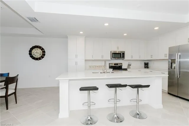 a kitchen with stainless steel appliances granite countertop a sink a stove a refrigerator and a refrigerator