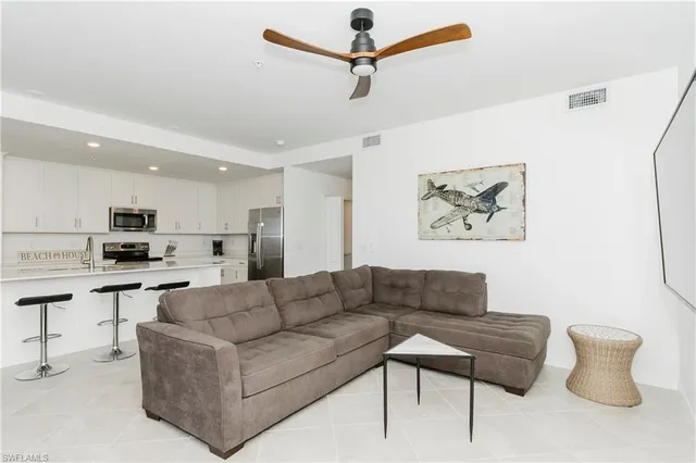 a living room with furniture kitchen view and a potted plant