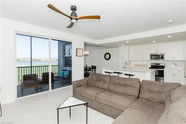 a living room with furniture kitchen view and large windows