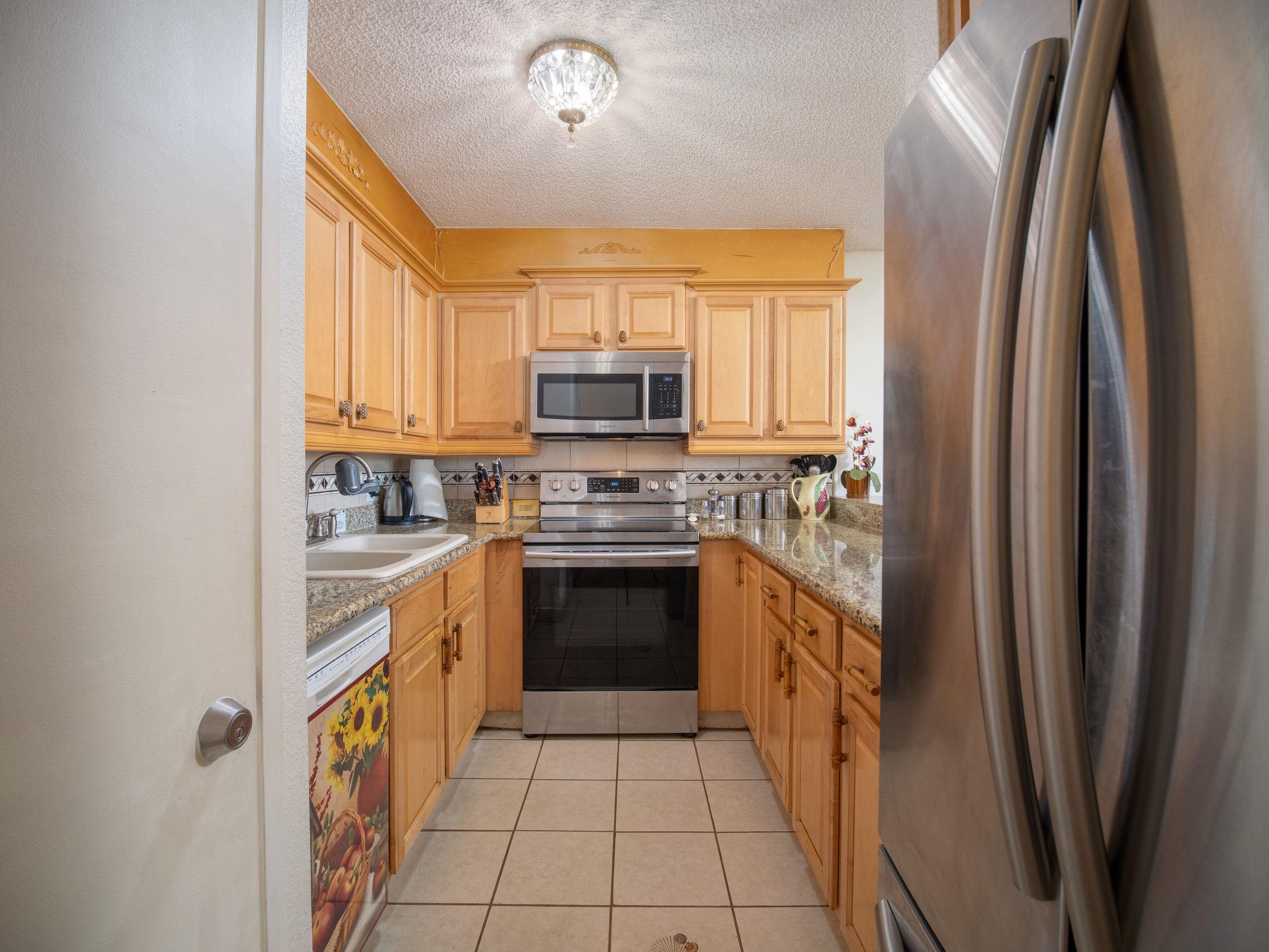 2695 South Kihei Road, Unit 7204 Kihei, HI 96753 - Photo 7 of 32 a kitchen with stainless steel appliances granite countertop a refrigerator sink and stove