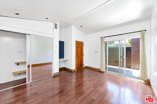 a view of an empty room with window and wooden floor