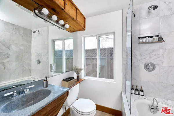 a bathroom with a granite countertop sink a toilet a mirror and shower