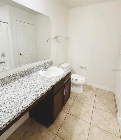 a bathroom with a granite countertop sink and a toilet