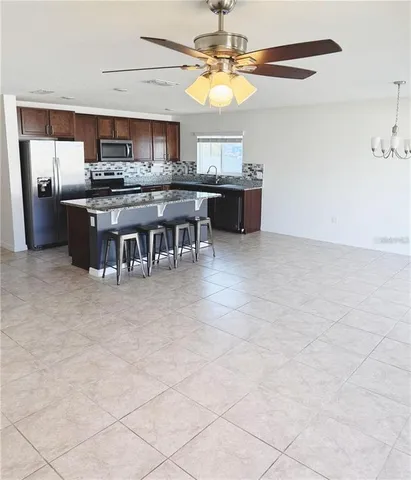 a kitchen with kitchen island granite countertop a stove top oven a sink a counter top space and cabinets