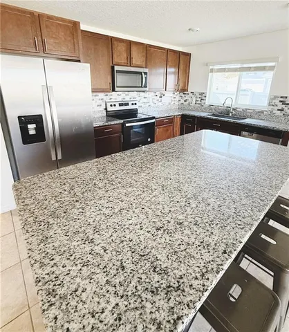 a kitchen with stainless steel appliances granite countertop a refrigerator and a sink