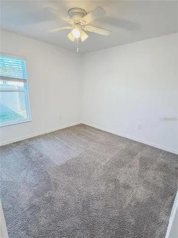 an empty room with a window and a ceiling fan