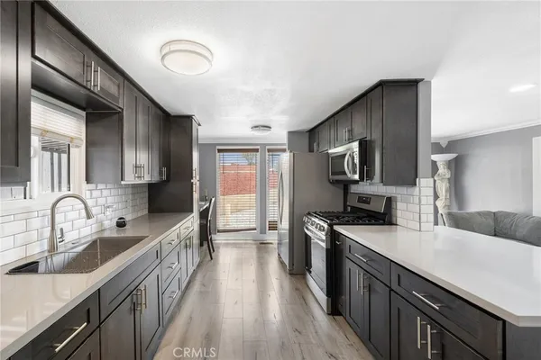 a kitchen with granite countertop a sink wooden cabinets and stainless steel appliances