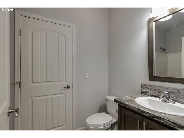 a bathroom with a granite countertop sink toilet and mirror