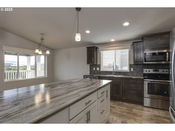 a kitchen with stainless steel appliances granite countertop a sink a stove a microwave and island