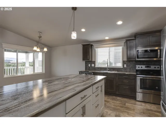 a kitchen with stainless steel appliances granite countertop a sink a stove a microwave and island