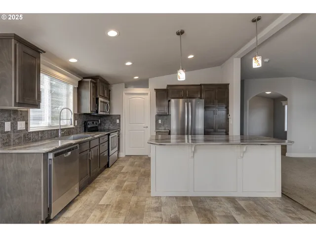 a view of a kitchen with kitchen island a counter top stainless steel appliances and cabinets
