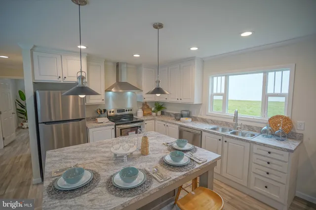 a kitchen with stainless steel appliances granite countertop a sink a stove a refrigerator cabinets and dining table