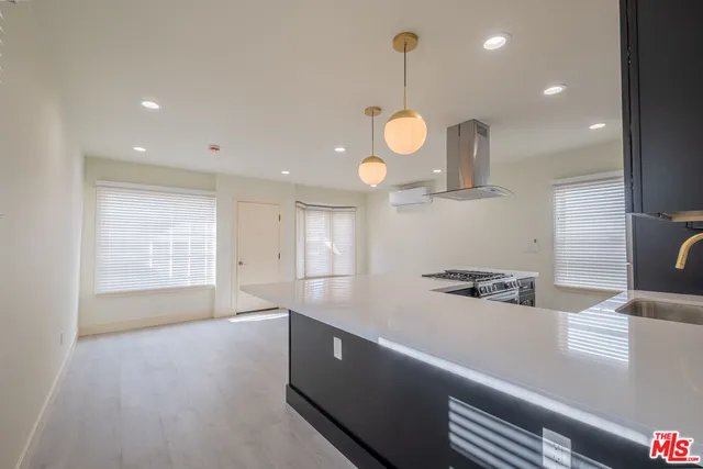 a large kitchen with stainless steel appliances a large counter top a stove and a wooden floors