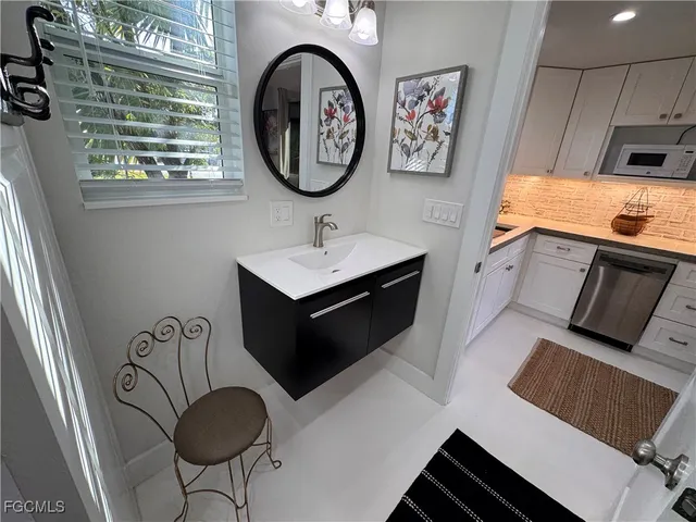 a kitchen with white cabinets and sink