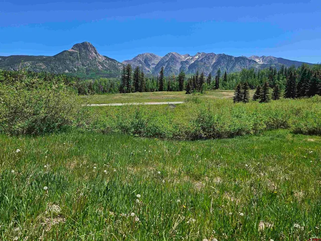 a view of a lush green outdoor space with a swimming pool and valleys in the background