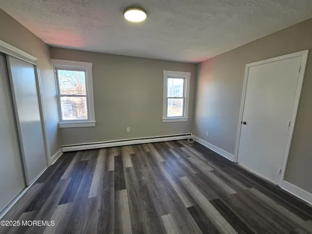 a view of an empty room with wooden floor and window