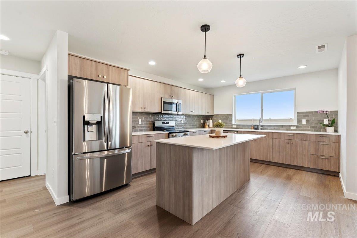 4086 North Kithnos Avenue Meridian, ID 83646 - Photo 9 of 29 Kitchen featuring stainless steel appliances, light brown cabinetry, pendant lighting, modern cabinets, and light wood-style floors