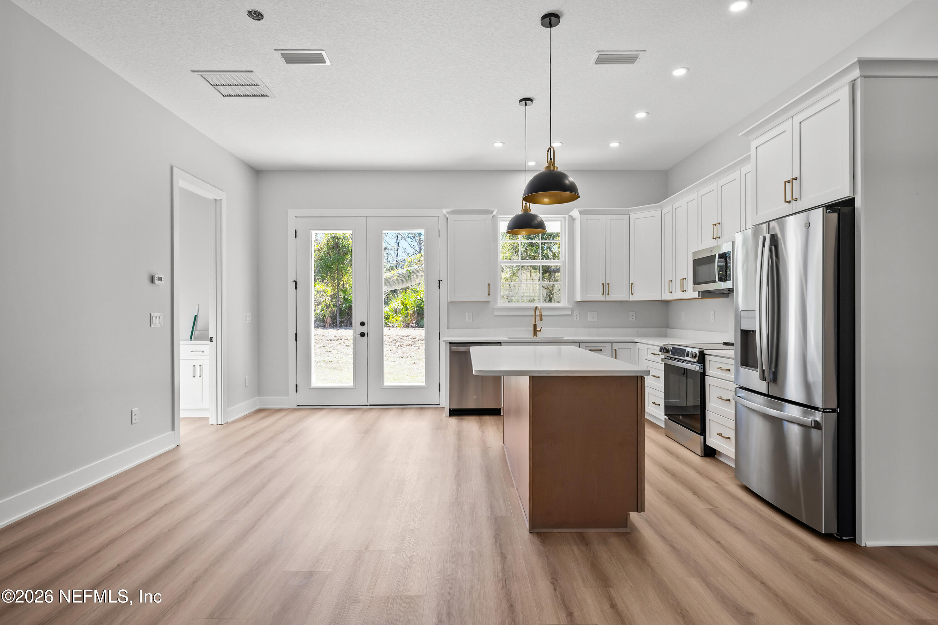 543 Palmetto Bluff Road Palatka, FL 32177 - Photo 8 of 23 a kitchen with a refrigerator a oven and white cabinets with wooden floor